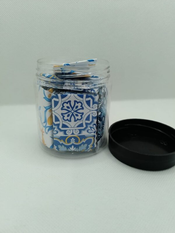 Pot transparent contenant des papiers pliés aux motifs bleus et citrons, servant de boîte à tirage au sort pour des invocations (Dua) quotidiennes.