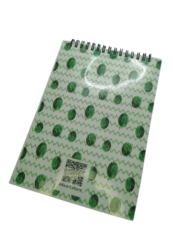 Dos du carnet de notes montrant un motif répété de pastèques vertes, une reliure à spirale noire et un QR code de la marque Ada.art.store.