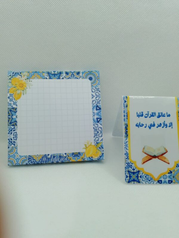 Gros plan sur un bloc-notes A6 quadrillé avec décor floral citron et un marque-page magnétique islamique posé à la verticale.